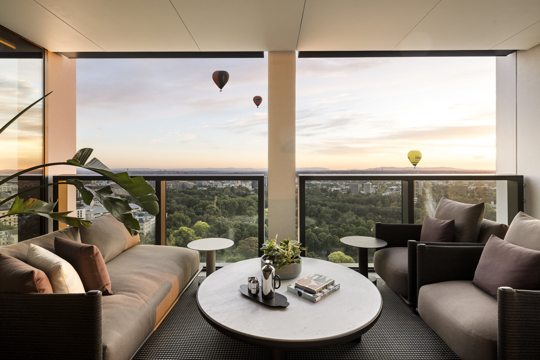 Apartment living room opening to a balcony, with hot air balloons over the parkland