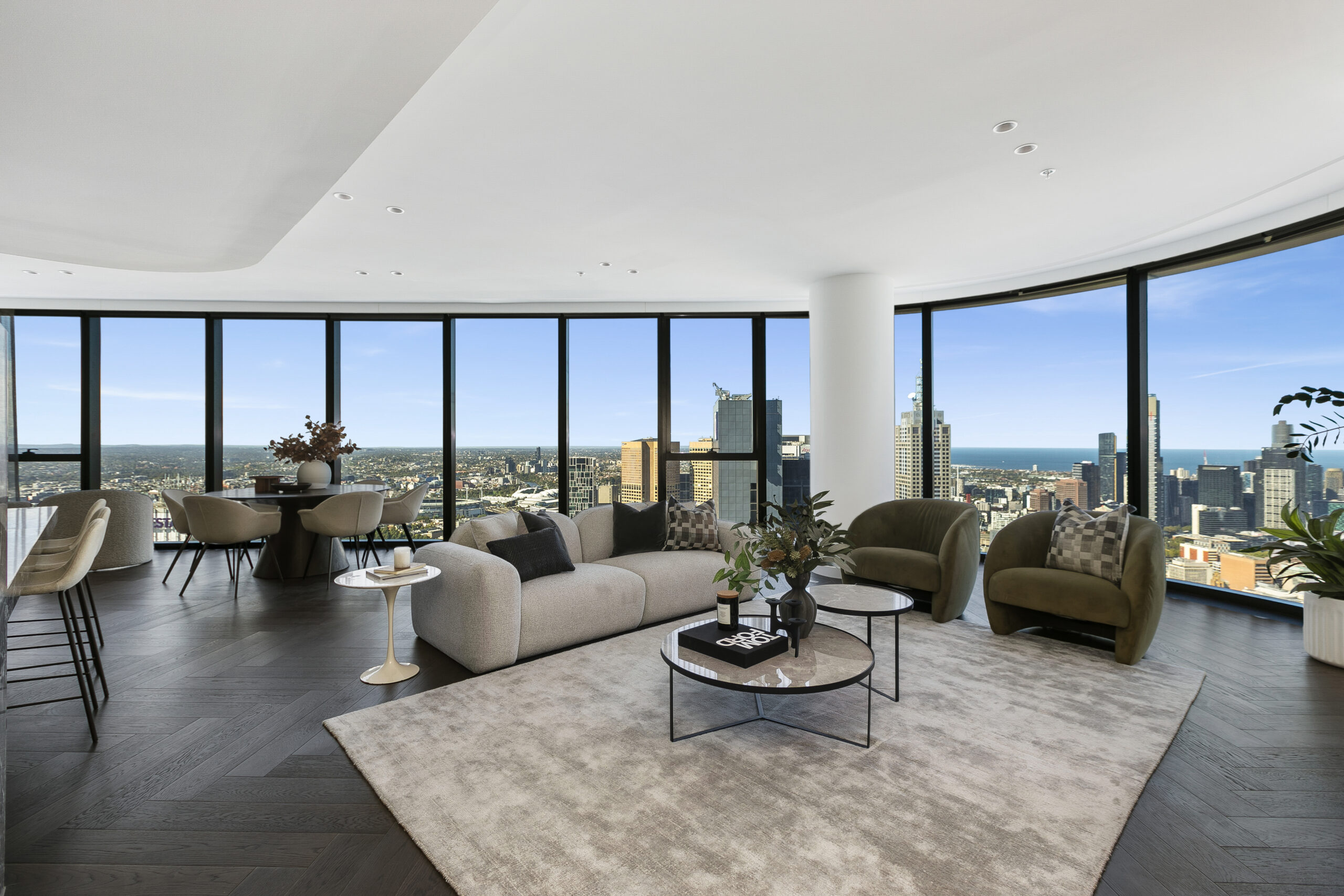 High-floor apartment living room with curved floor-to-ceiling windows and city views